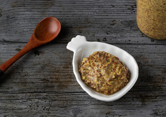 Old mustard on a white plate in rustic background