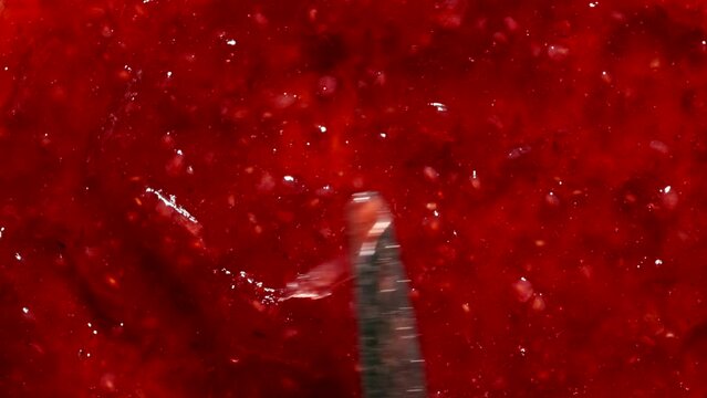 TOP VIEW: Knife spreads a raspberry jam