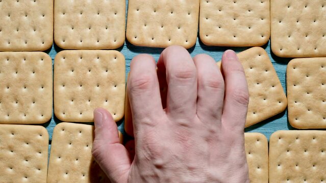 TOP VIEW: Human hand takes a cracker cookie rough