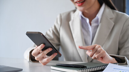 Cropped shot of female employee sitting in office and typing text message on mobile phone