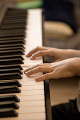 Fototapeta premium Hands of the child playing piano. Initiation to music, experiences and learning, concept. Closed image and shallow depth of field.