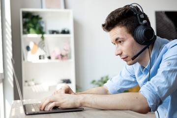 Obraz na płótnie Canvas Young handsome male customer support phone operator with headset working in call center..