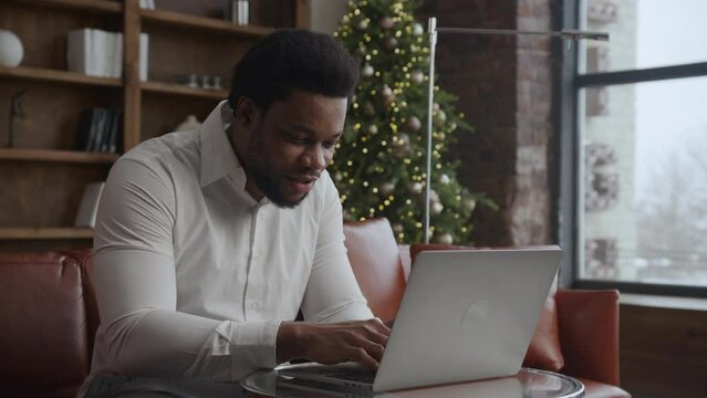 Young adult african american entrepreneur working happy on his laptop on Christmas