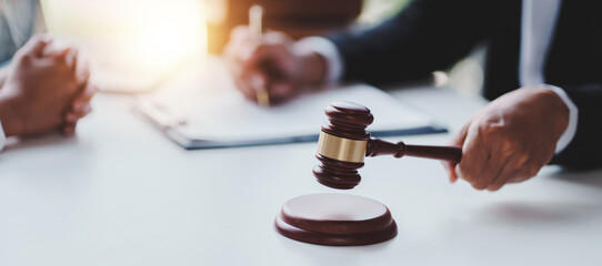 concept of justice and law A male judge in the courtroom on a wooden table and a male counselor or lawyer working in the office. Law, advice and justice concepts.