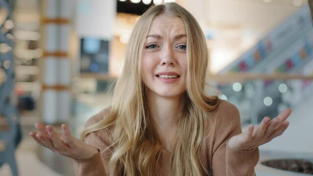 Puzzled Caucasian woman upset furious girl blonde lady indoor asks so what happened holding hands v looking dissatisfied at camera confused angry misunderstanding irritation reaction negative emotions