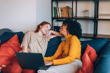 two young comfortable girls at home on couch with laptop