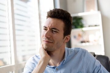 Feeling exhausted.Frustrated young man looking exhausted and massaging his neck while sitting at his working place.