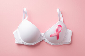 Breast cancer awareness concept. Top view photo of white brassiere with pink silk ribbon on...