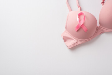 Breast cancer awareness concept. Top view photo of pink satin ribbon attached to pink brassiere on...