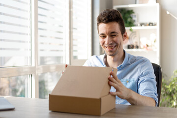 Excited caucasian man customer receive good parcel open cardboard box at home satisfied with great purchase, happy male consumer unpack package look inside overjoyed by postal shipping delivery.
