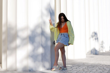 Attractive young girl with long hair wearing jeans shorts, orange top and platform flip-flops...