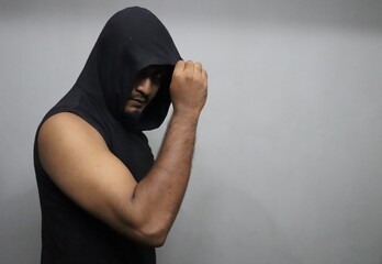 A man in a black sleeveless hooded vest with bulky triceps muscles.