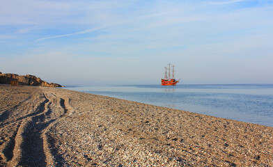 Fototapeta na wymiar Red sailing ship in the sea in sunset time