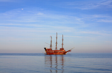 Red sailing ship in the sea in sunset time	
