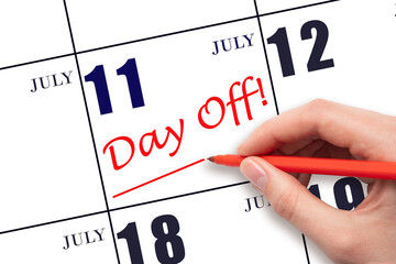 Hand writing text DAY OFF and drawing a line on calendar date 11 July. Vacation planning concept.
