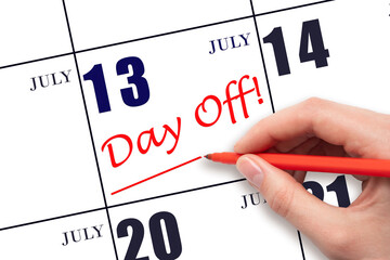 Hand writing text DAY OFF and drawing a line on calendar date 13 July. Vacation planning concept.