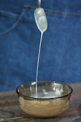 white liquid chocolate flows down a teaspoon into a small plate. chocolate for cake decoration