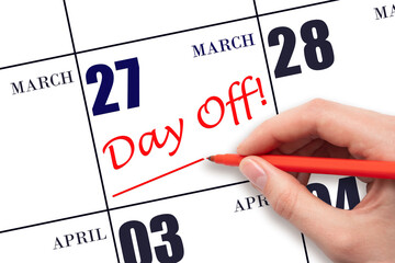 Hand writing text DAY OFF and drawing a line on calendar date 27 March. Vacation planning concept.