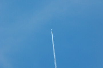 A single plane making vapour trail on a blue, cloudless sky, space for text, no people, 