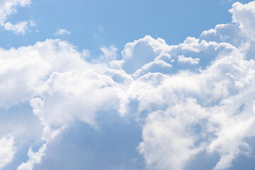 White thick and fluffy cumulus clouds in the light blue sky, close up. Beautiful cloudscape