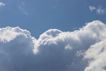 Fototapeta na wymiar White thick and fluffy cumulus clouds in the light blue sky, close up. Beautiful cloudscape