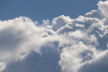 Naklejka na ściany i meble White thick and fluffy cumulus clouds in the light blue sky, close up. Beautiful cloudscape