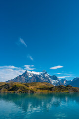 Peaks of Torres seen from Pehoe Lago with turquoise water in Torres del Paine National Park, Patagonia, Chile, at sunny day and blue sky.
