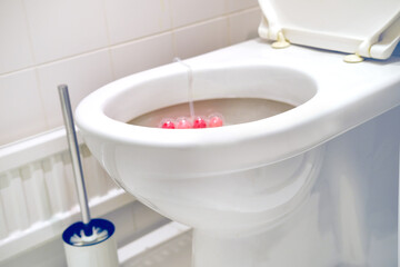 white faience toilet bowl, home toilet, disinfectant flavoring balls on the side of the toilet...