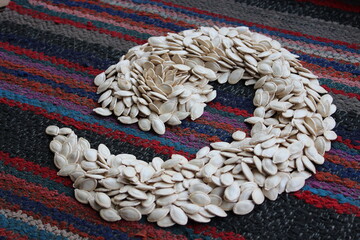 Heap of pumpkin seeds on an old carpet.