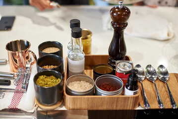 Set of seasoning in professional kitchen with spoons. Close up. peppercorns, shafran; bottles of oils, salt; dry garlic