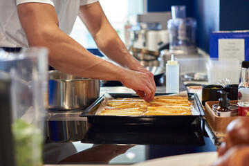 Chef hands preparing potato fries on the baking tray for roasted in oven. Professional kitchen. Food concept