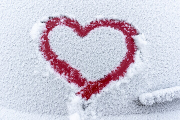 Snow red heart on the car window with copy space. Heart sign in fresh snowflakes. Heart shape...