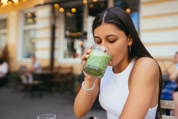A young woman in a cafe drinks a green drink ice latte.