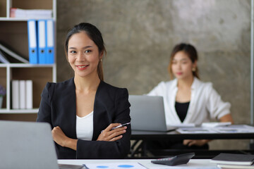 Portrait of a businesswoman or female manager working on a laptop in the office. Looking at camera.