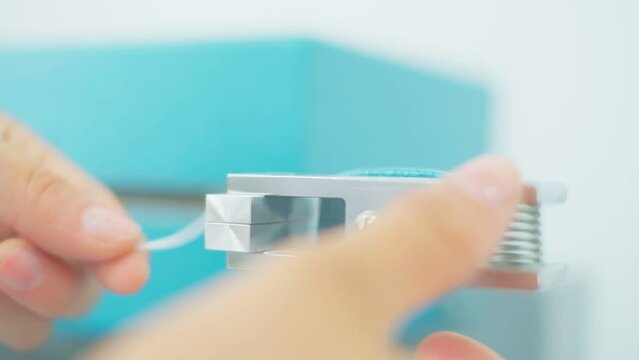 Closeup of polymer thread for plastic sack bags is installed to strength test machine