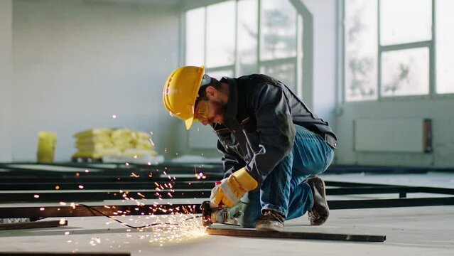In a large construction site hard working man using the disc welding machine to cut some metals and creating big sparks