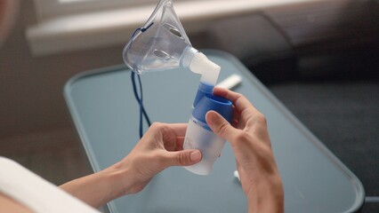Female hands is opening a medicine and pours into inhaler