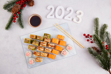 2023 Happy new year greeting card. Flat lay. Assorted set of various sushi rolls with tuna, salmon,...