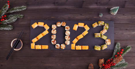 2023 Happy new year greeting banner. Flat lay. Assorted set of various sushi rolls with tuna,...