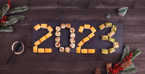 Fotobehang 2023 Happy new year greeting banner. Flat lay. Assorted set of various sushi rolls with tuna, salmon, eel, avocado, vegetables. The sushi rolls are laid out in numbers 2023.  © Viktoriya