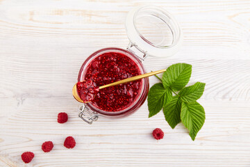 Jar of raspberry jam and fresh berries on light wooden background. Top view. 