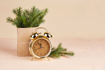 Happy New Year or Merry Christmas Greeting card. Spruce branches in a kraft bag, a golden alarm...