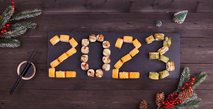 2023 Happy new year greeting banner. Flat lay. Assorted set of various sushi rolls with tuna, salmon, eel, avocado, vegetables. The sushi rolls are laid out in numbers 2023. 