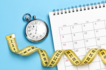 Yellow measuring tape on a calendar with a stopwatch