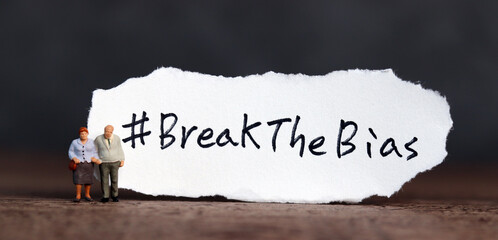 Torn paper with the word ‘BreakTheBias' written on it. Break the bias campaign with miniature old...