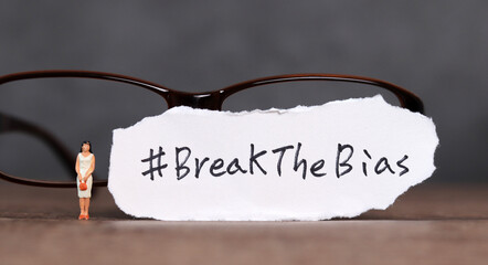 Torn paper with the word ‘BreakTheBias' written on it. Break the bias campaign with miniature...