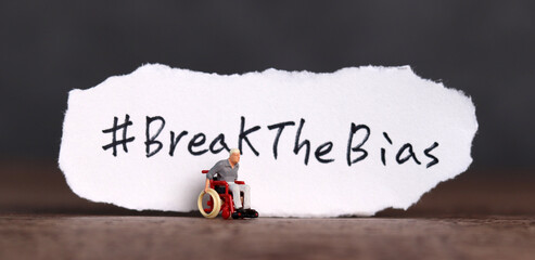 Torn paper with the word ‘BreakTheBias' written on it. Break the bias campaign with a miniature...