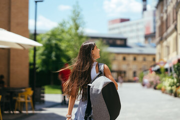 Young woman with backpack walks around the city. - obrazy, fototapety, plakaty