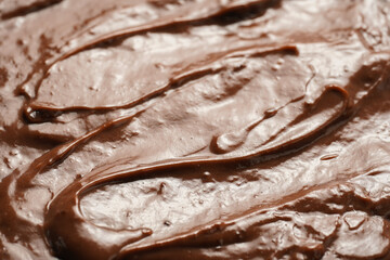 a close-up on chocolate ganache or pudding with swirls and spreads filling the frame, selective focus