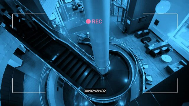 High angle security camera footage of two businessmen walking down stairs in lobby of modern luxury hotel